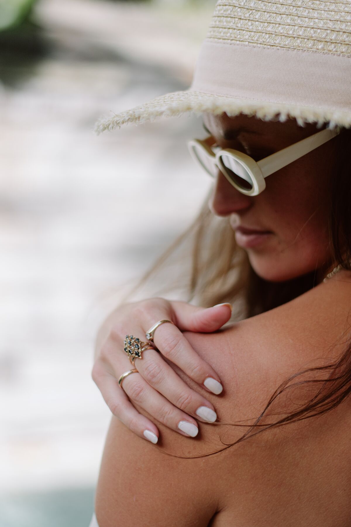 Portrait in a straw hat and white sunglasses, hand resting on her shoulder