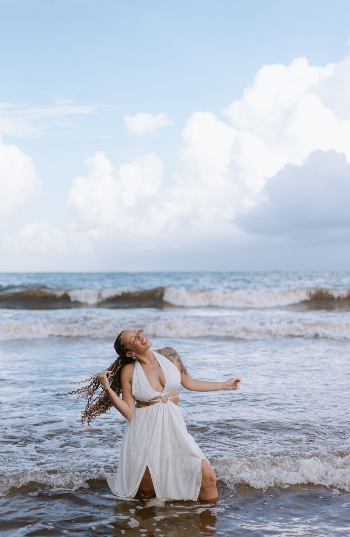 Woman in a white dress moving through the surf