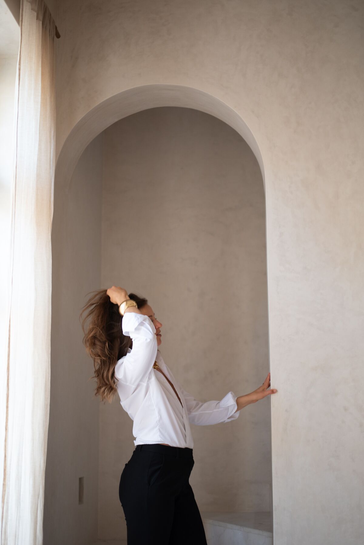 Woman in a white shirt and black trousers inside a plaster archway